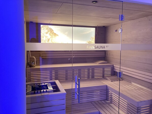 A sauna with a wooden interior, a bench, and a window with a view of a mountain.