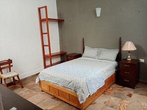 Cozy retreat with a comfortable bed, nightstand, and chair.