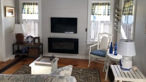 A cozy living room with a fireplace, a television, and a dining area with a table and chairs. - OCEAN VIEWS & A/C in cozy condo w/upscale finishes!- STEPS TO PRIVATE BEACH (Mashpee)