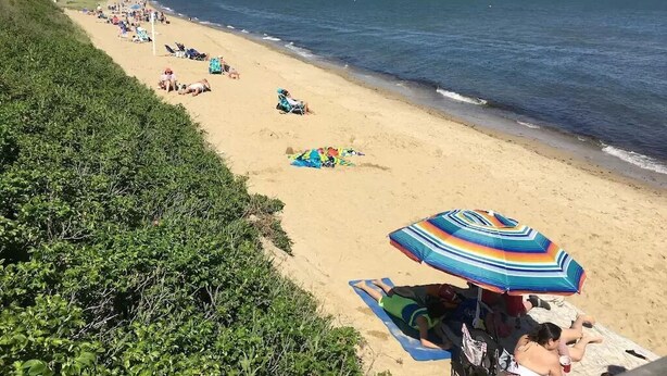 A beach with people sunbathing, some under umbrellas. - OCEAN VIEWS & A/C in cozy condo w/upscale finishes!- STEPS TO PRIVATE BEACH (Mashpee)