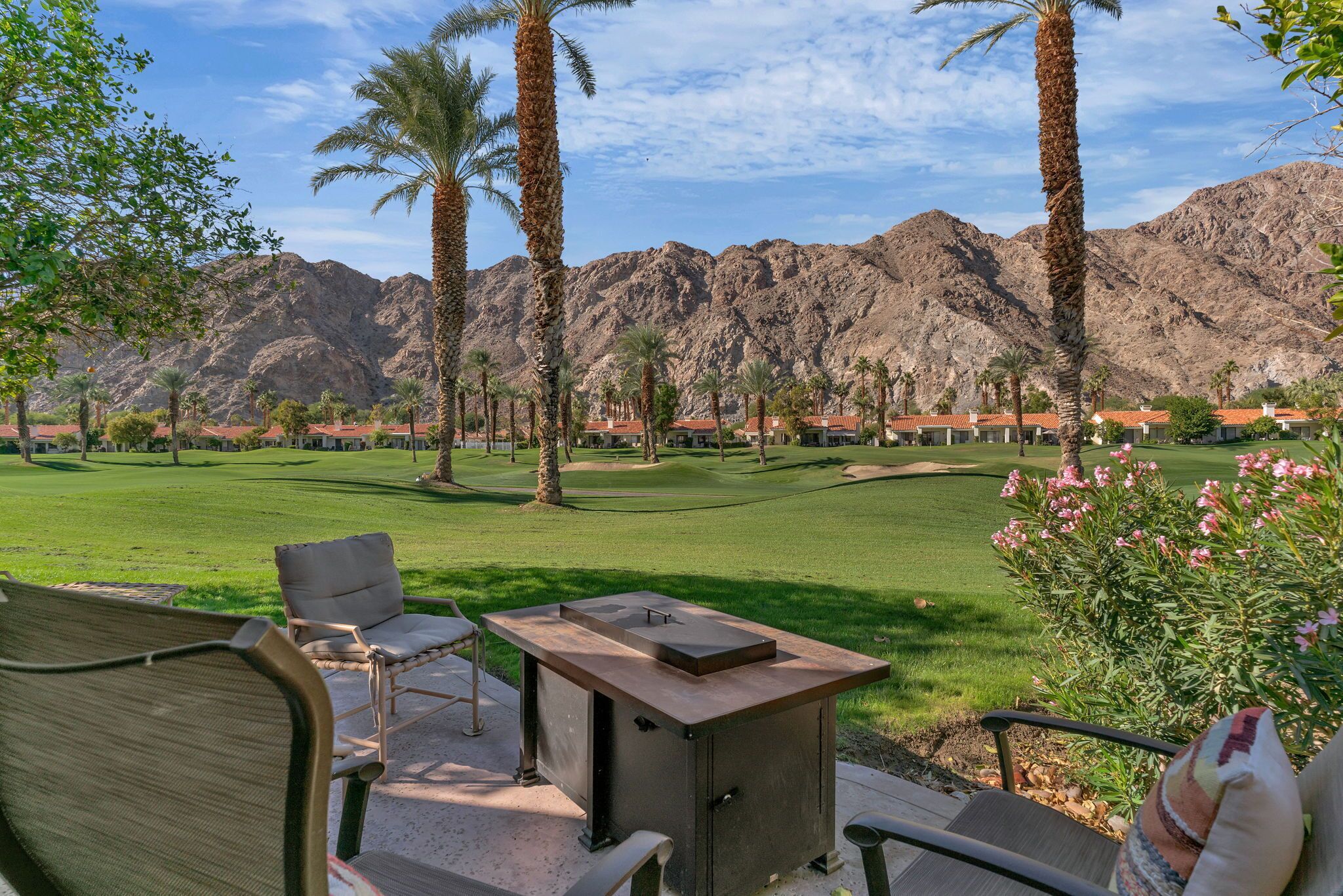 A golf course with palm trees and mountains in the background.