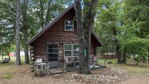 Une cabane en rondins avec une véranda, un banc et une petite table.
