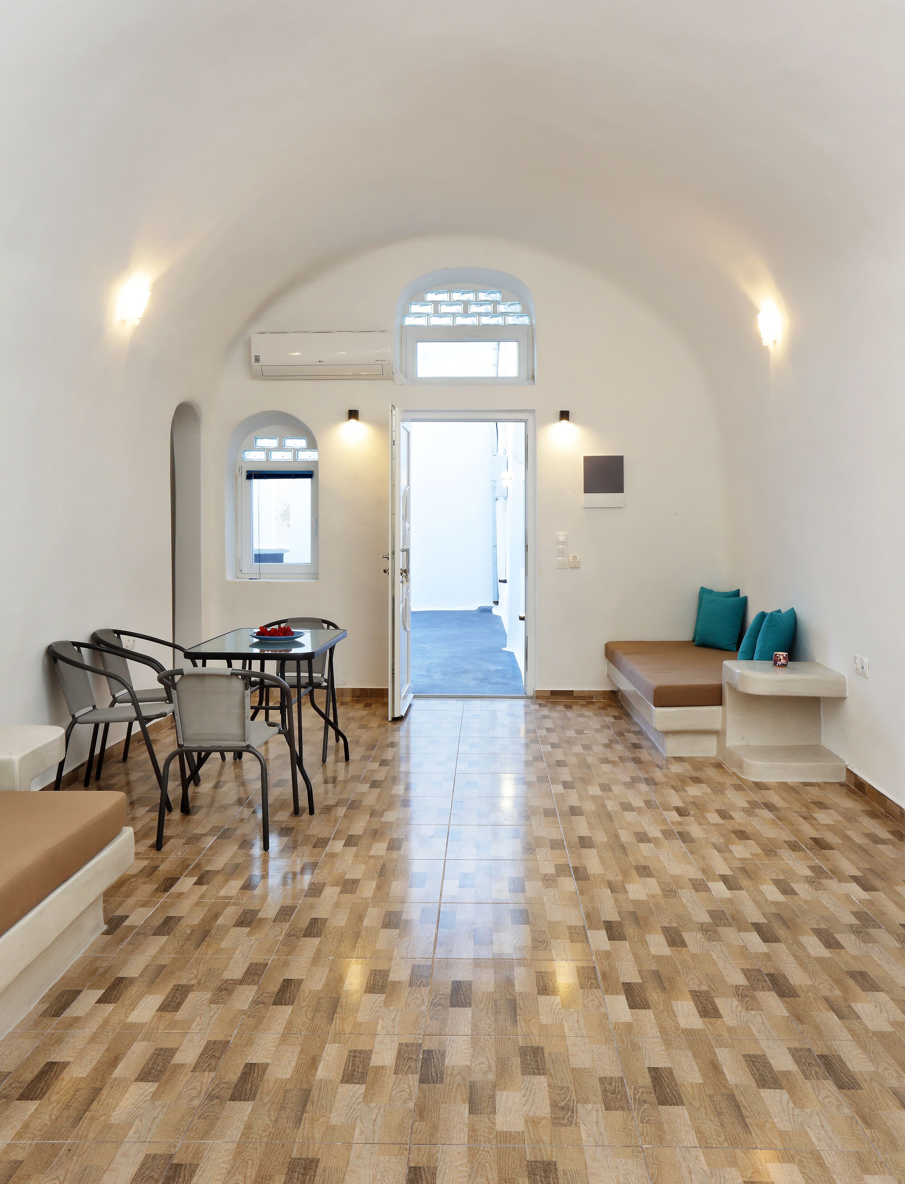 A spacious room with a dining table and chairs, a bench, and a view of the outside.
