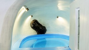 Ein Wellnessbereich mit einer blauen Badewanne und Stufen, die zu ihr führen.