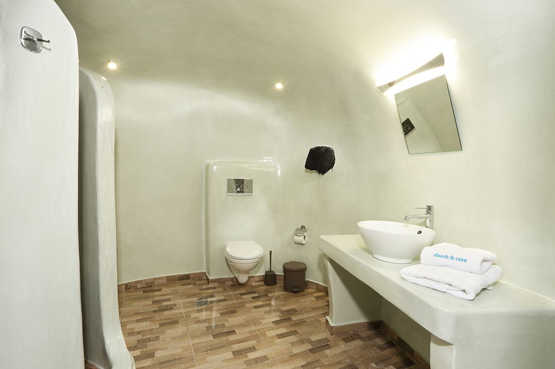 A bathroom with a toilet, sink, and mirror.