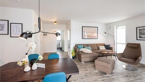 A modern living room with a dining area, featuring a sofa set, a coffee table, and a dining table with chairs. - Beautiful apartment in Rechlin with WiFi (Rechlin)