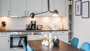 A modern kitchen with stainless steel appliances, a dining table with chairs, and a pendant light. - Beautiful apartment in Rechlin with WiFi (Rechlin)