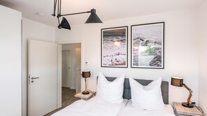 A hotel room with a bed, two bedside tables, two lamps, and two framed pictures on the wall. - Beautiful apartment in Rechlin with WiFi (Rechlin)
