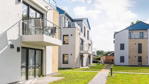 A modern residential building with glass balconies, a paved walkway, and a clear sky. - Beautiful apartment in Rechlin with WiFi (Rechlin)