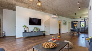 A spacious living room with a flat-screen TV, wooden flooring, and a dining area with a modern table and chairs. - Modern Villa Leonardo with an outdoor pool (Porec)