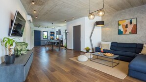A modern living room with a dark blue sofa, a coffee table, and a TV mounted on the wall. - Modern Villa Leonardo with an outdoor pool (Porec)