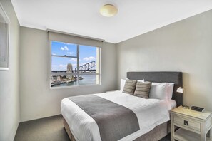 Relax in a serene space with a large bed and a stunning view of a bridge and water.