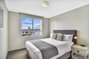 Relax in a serene space with a large bed and a stunning view of a bridge and water.