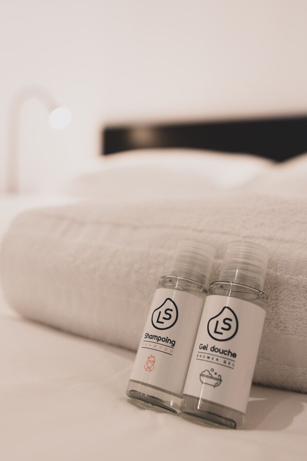 Dos botellas de champú y gel de ducha sobre una cama con una toalla blanca doblada.