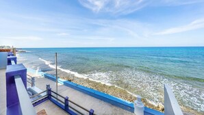 A coastal view with a clear sky, a rocky shoreline, and a blue railing. - Castillito del Caribe 4 Bedrooms (Isla Mujeres)