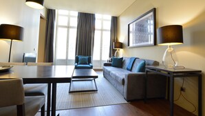 A modern hotel room with a dining table, sofa, and two lamps. - Dom Luis I Prestige Flat 17 (Lisboa)