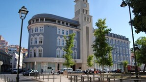 A historic building with a clock tower, a round corner, and a pedestrian area with trees. - Dom Luis I Prestige Flat 17 (Lisboa)