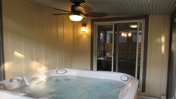 Un jacuzzi con ventilador de techo y puerta de vidrio que da a un patio.