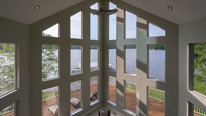 Una habitación con amplias ventanas que ofrecen vistas a un lago y a una terraza.