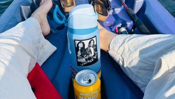 Un bote con una caña de pescar, una botella de agua y una lata de jugo de mango.