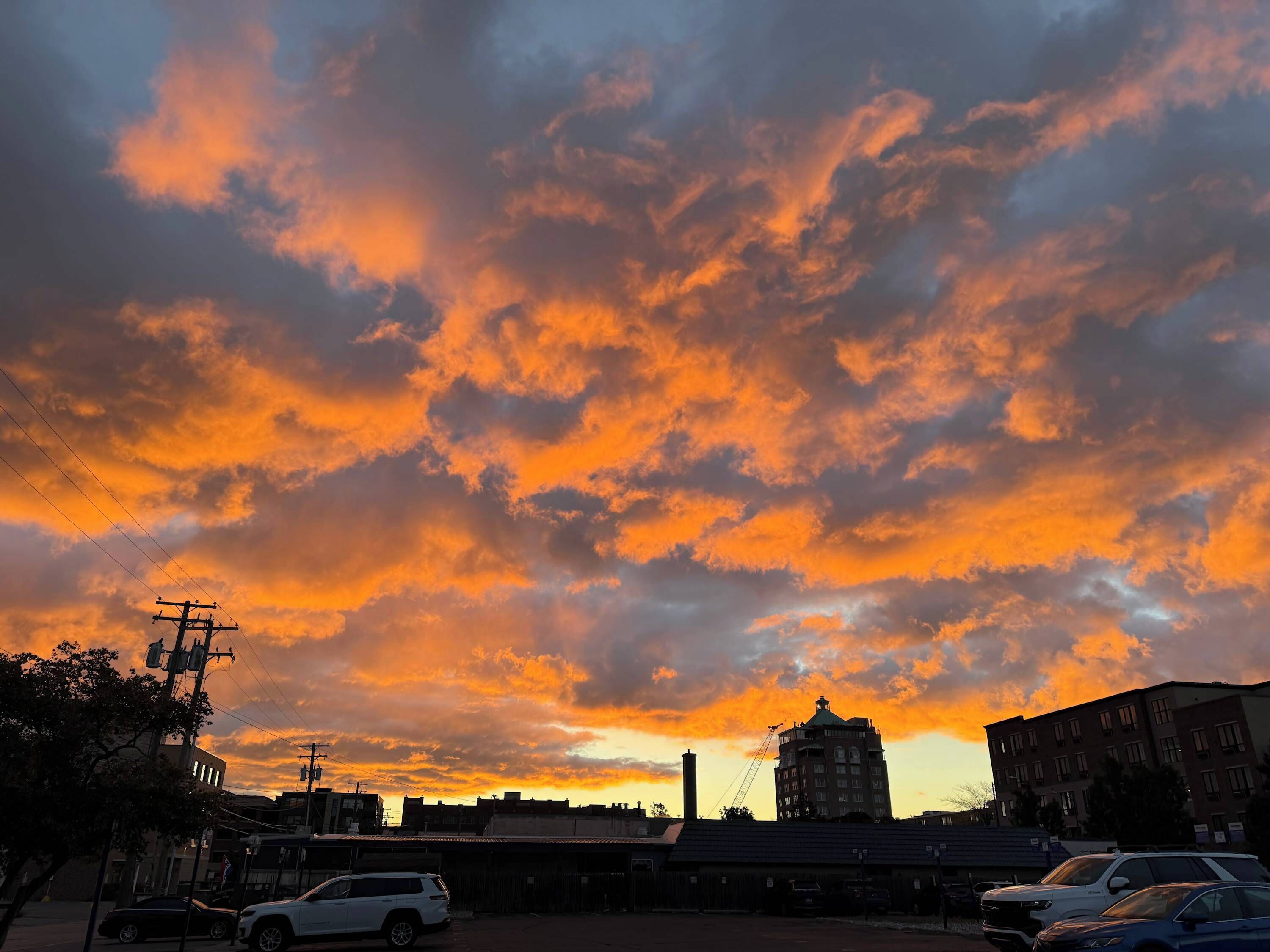 A sunset over a cityscape with buildings and a crane.