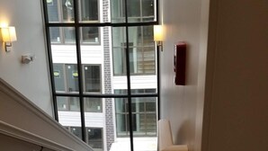 Een trap met beklede treden die uitkomt op een plateau met een groot raam met uitzicht op een gebouw.
