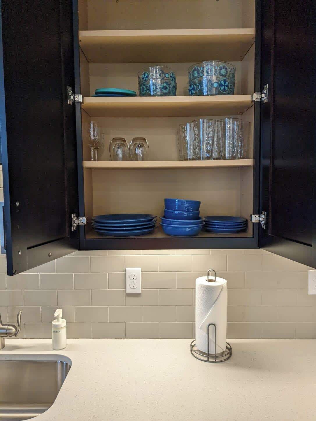 A kitchen with a built-in cabinet, a sink, and a toilet paper holder.