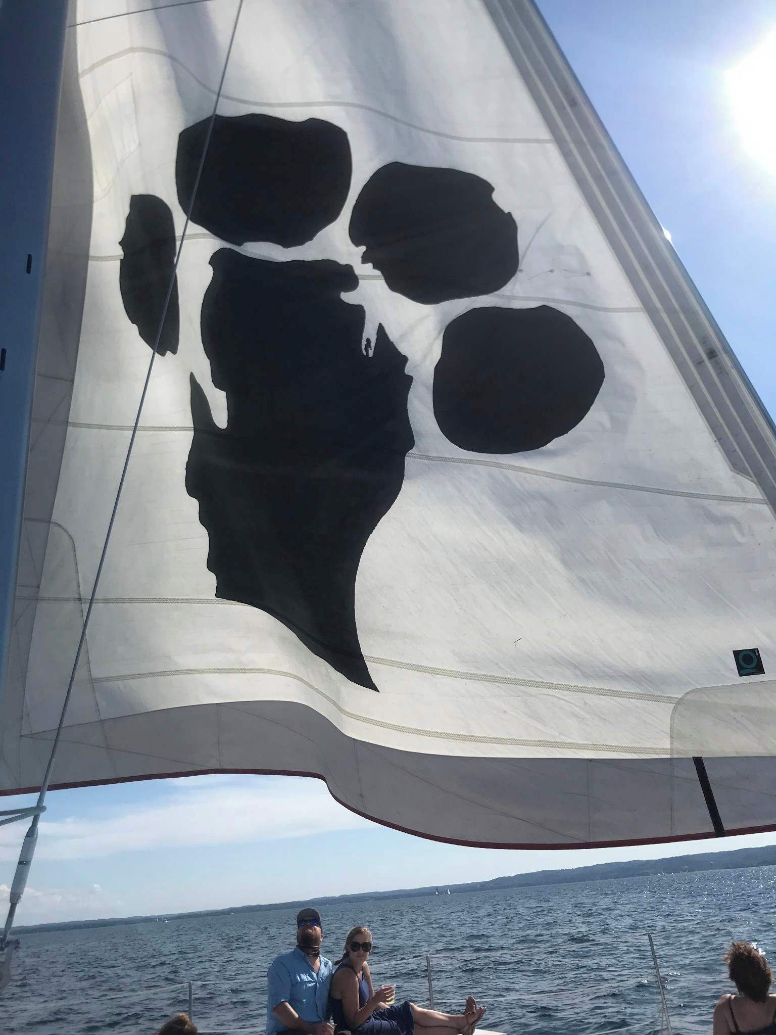 Un voilier doté d’une grande voile ornée de la silhouette d’un visage.