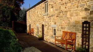 A stone building with a stone staircase leading to a wooden bench and a door. - The Oaks - Award Winning Barn Conversion In Hope Village Near To Castleton (Hope)