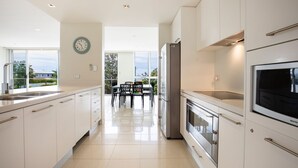 Una cocina moderna con armarios blancos, electrodomésticos de acero inoxidable y una zona de comedor con mesa y sillas.