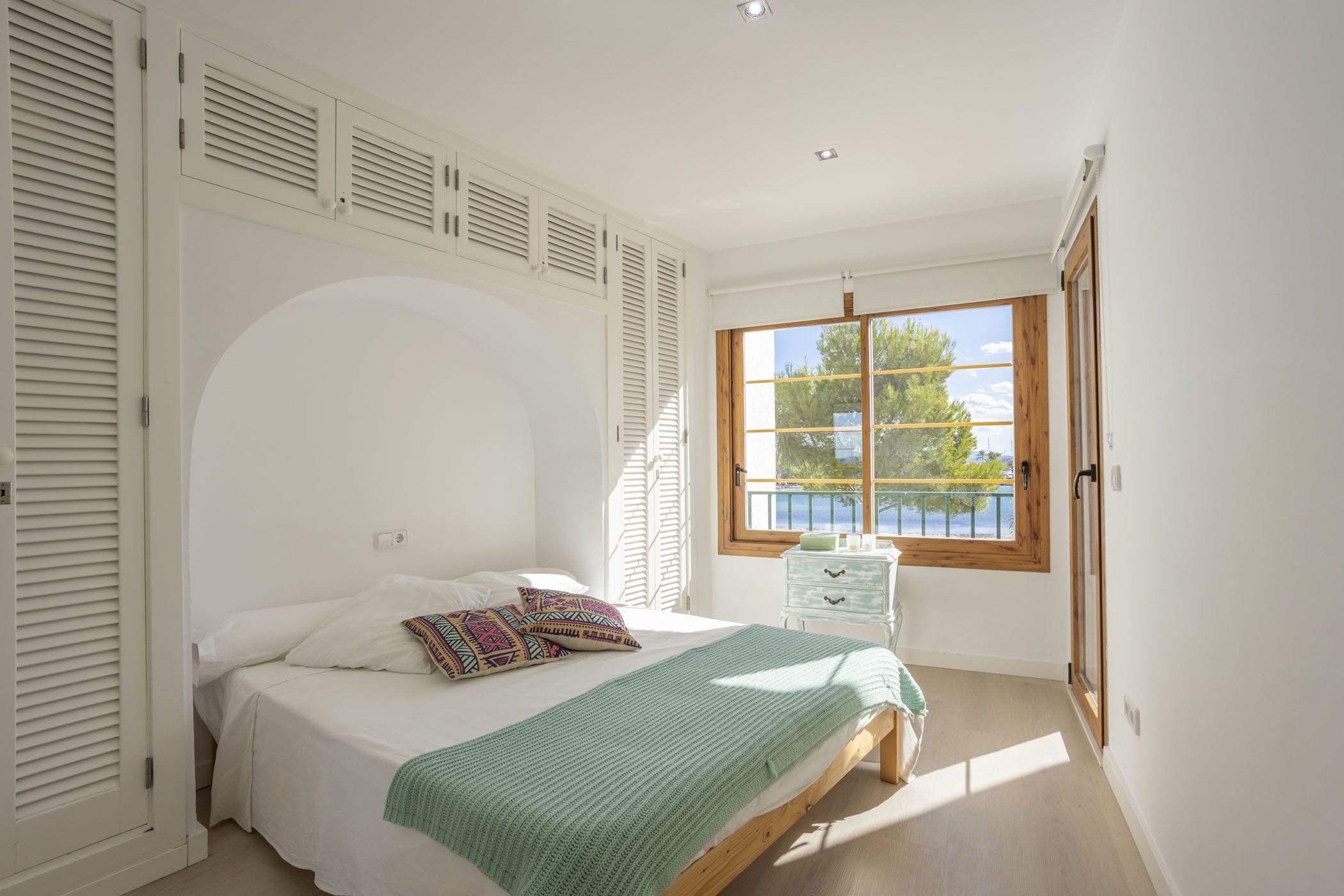 A bedroom with a bed, a window with a view, and a door.