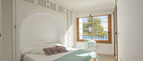 A bedroom with a bed, a window with a view, and a door.