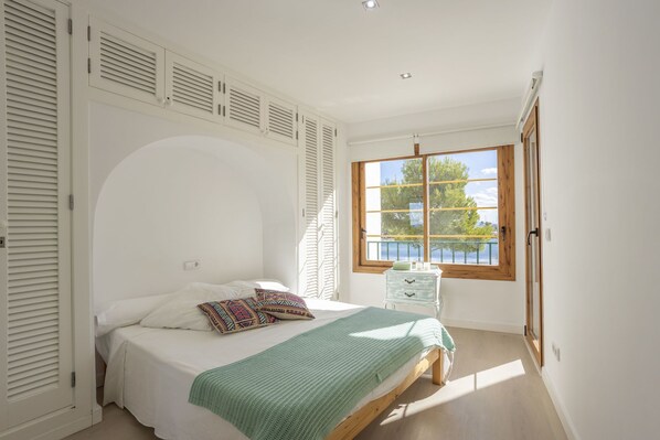 A bedroom with a bed, a window with a view, and a door.