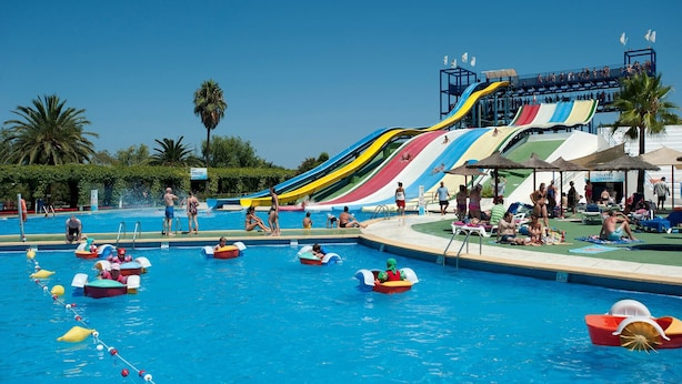 Una piscina con tobogán acuático y botes hinchables.