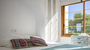 Un dormitorio con cama, almohadas, cómoda y ventana con persianas.