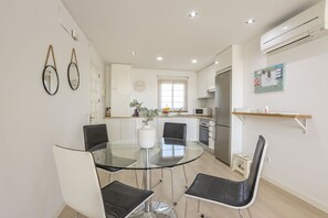 A modern kitchen with white cabinets, a glass dining table, and black chairs.