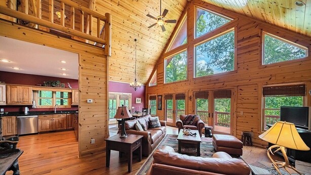 A spacious wooden cabin interior with a living area, kitchen, and large windows.