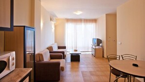 A compact living space with a sofa set, a dining table, a television, and a microwave. - Dream Holiday Aparthotel (Nessebar)