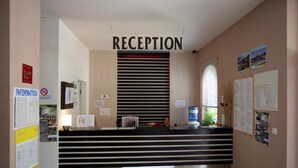 A reception area with a black and white striped counter, a sign reading "RECEPTION", and various informational posters on the walls. - Dream Holiday Aparthotel (Nessebar)