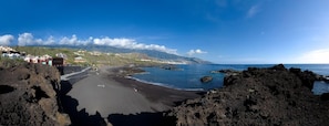 Una carretera costera que lleva a una playa con terreno rocoso y una vista despejada del océano.