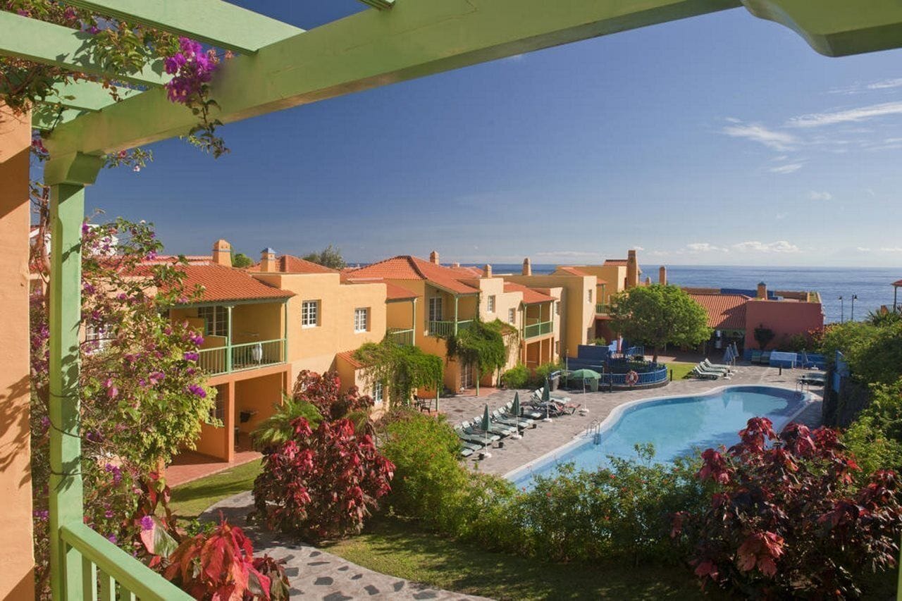 A hotel with a pool, outdoor seating, and a view of the sea.