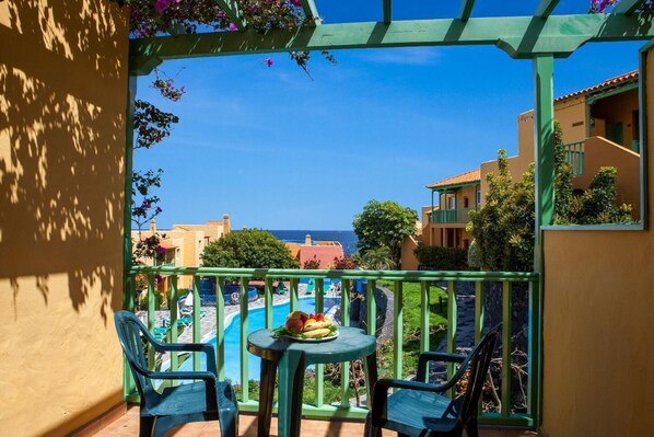A balcony with a view of a pool and the sea, featuring green railings and a table with chairs. - La Caleta (Brena Baja)