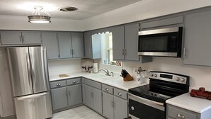 Una cucina moderna con mobili grigi, elettrodomestici in acciaio inossidabile e una tovaglia a scacchi.