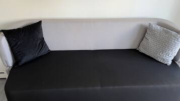 Ein graues Sofa mit schwarzen und grauen Kissen.