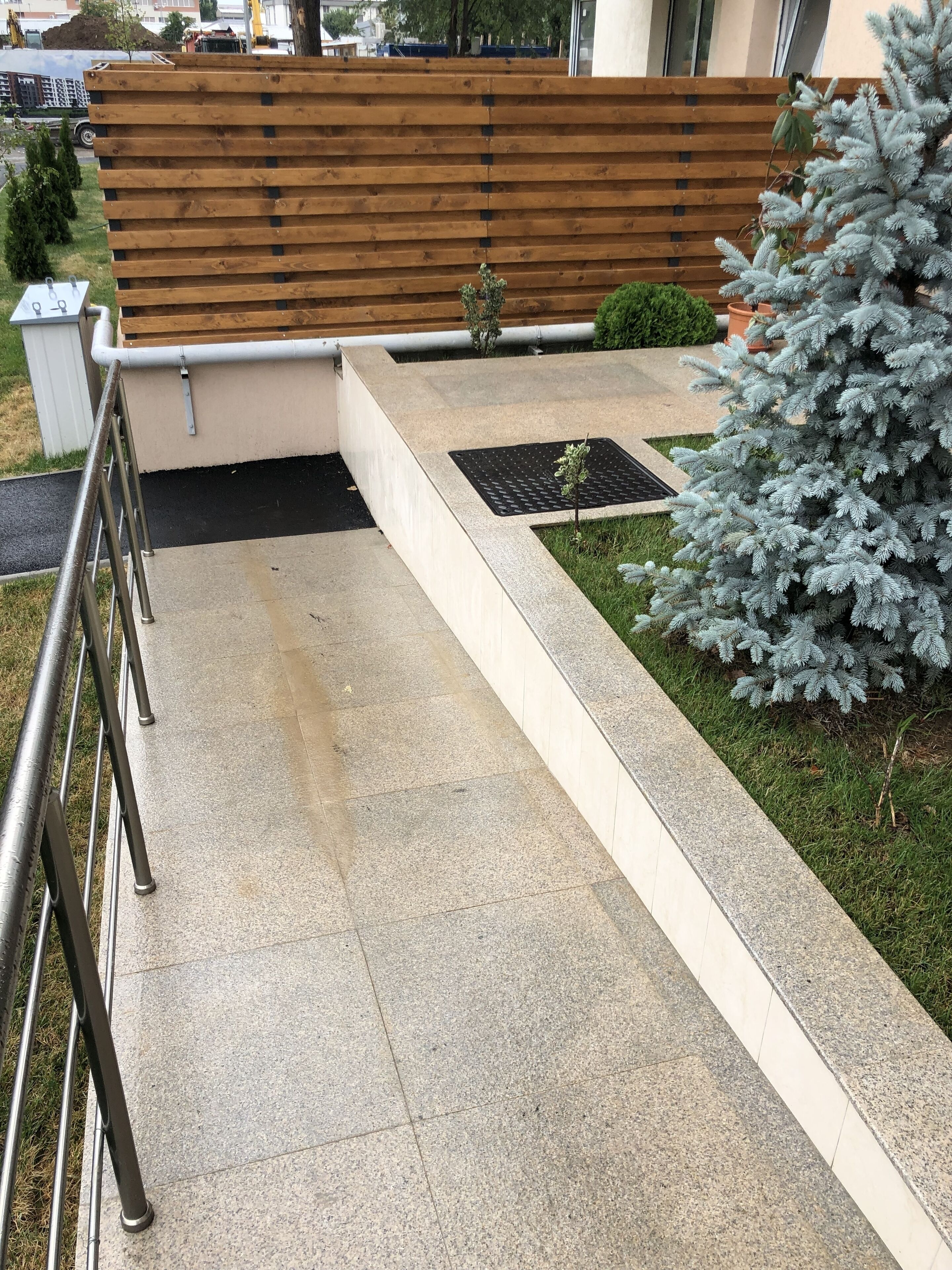 A concrete pathway leading to a wooden bench with a metal railing on one side.