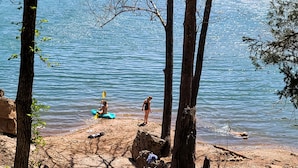 Un environnement naturel comprenant une étendue d’eau, des arbres et une zone sablonneuse.