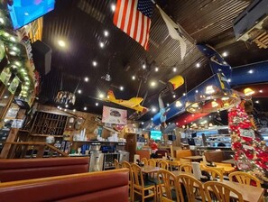 Enjoy a casual meal in a warm and inviting space with wooden tables and a bar area.