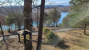 Un cadre paisible au bord du lac, avec un banc en bois et une lanterne, entouré d’arbres et offrant une vue dégagée sur le lac et les montagnes lointaines.