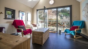 A spacious room with a high ceiling, large windows, and a view of the outdoors. - Rock Cottage - 3 Bedroom Holiday Home - Fishguard (Fishguard)