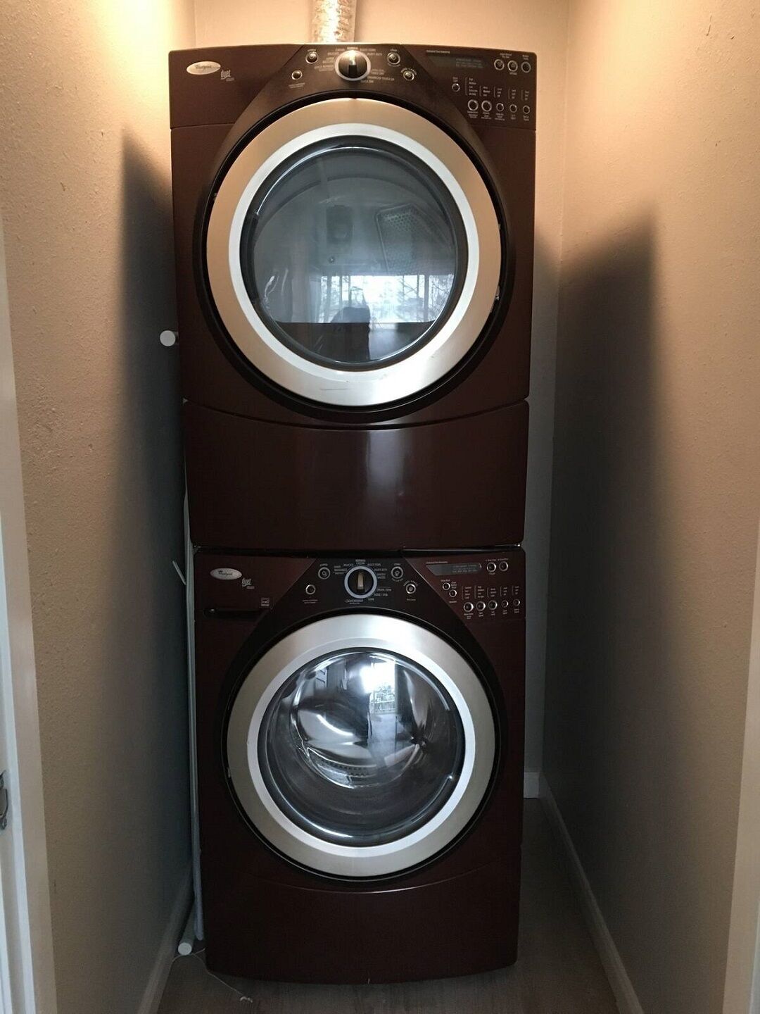 A compact, two-door front-loading washer and dryer unit in a narrow hallway.